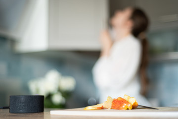 Cooking with the functions of a smart home. A young woman uses a voice assistant in her kitchen...