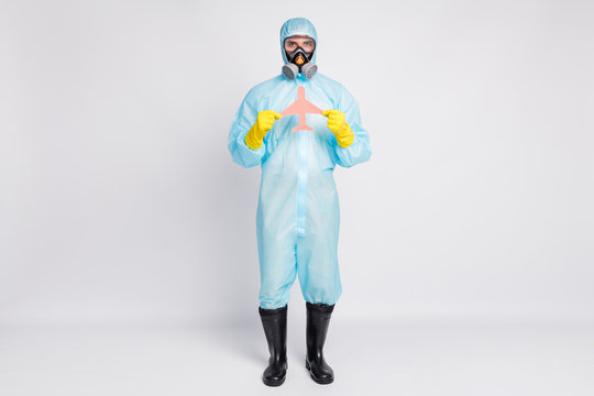 Full Length Photo Of Man Hold Paper Card Plane No Travel Covid19 Quarantine Wear White Suit Hazmat Yellow Rubber Latex Gloves Goggles Breathing Mask Isolated Gray Color Background