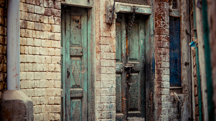 Wooden green door with brick wall and a pole