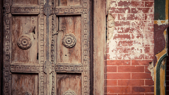 Wooden doors with carving next to brick walls