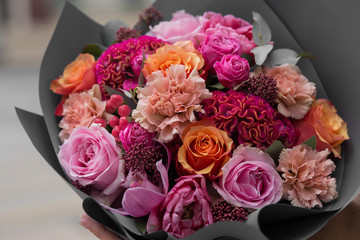 Beautiful flower bouquet with roses, cloves in gray paper close up. Pink roses. Flower shop. Florist.