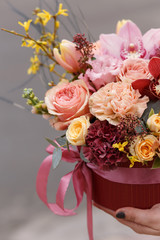 Colorful bouquet in red box with roses, cloves,tulips, orchid. Florist shop.  