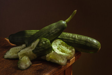 Juicy green cucumber, on a wooden table, with a dark background, soft light. Imitation of a Dutch...