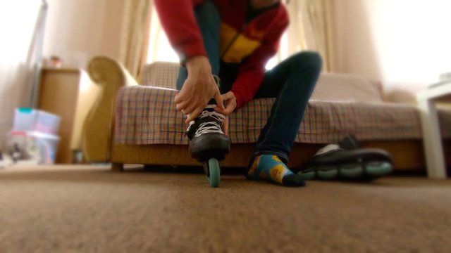 Man wearing skates at home sitting on couch - rollerblades