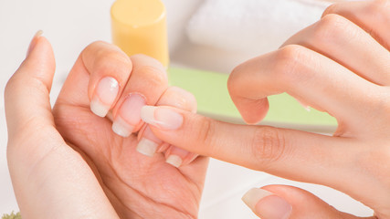 Manicure. A woman applies cuticle oil to her nails. Nail care. Natural long nails. Unpainted. Moisturizing. French manicure. Skin care, SPA, beauty salon. Manicure set.