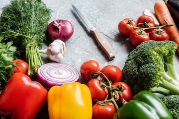 colorful fresh ripe vegetables with knife on grey concrete surface