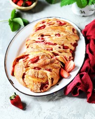 Yeast babka with strawberries and sugar in a dish on a gray background