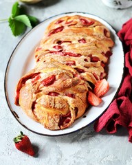 Yeast babka with strawberries and sugar in a dish on a gray background