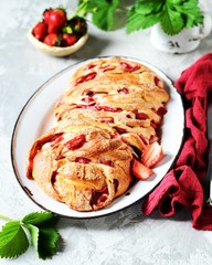 Yeast babka with strawberries and sugar in a dish on a gray background
