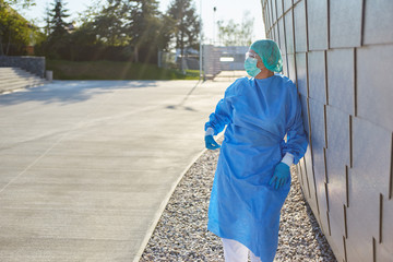 Doctor in protective clothing takes break during coronavirus pandemic in front of clinic