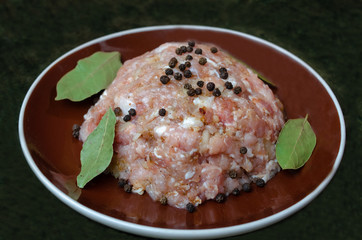 fresh minced meat on a plate with black pepper and Bay leaf.
