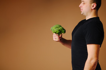 Fit man is holding broccoli. Healthy organic food.