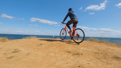 Fototapeta premium Young male on the bicycle with helmet ride on the beach 