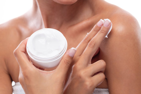 Photo of young girl rubbing body cream on her skin