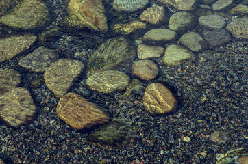 textured pebbles in water with reflection of a sunlight is well suited for background