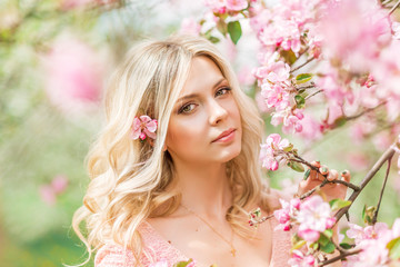 Obraz na płótnie Canvas portrait of a blonde woman in pink flowers. Spring garden