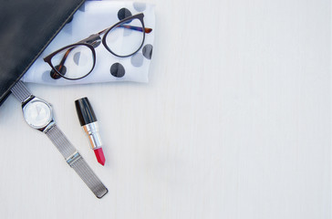Fashionable concept of a women's handbag. White women's headscarf with black polka dots, glasses, watch and bright red lipstick on white background. Flat lay.