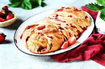 Yeast babka with strawberries and sugar in a dish on a gray background