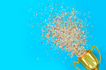 image of little gold cup , concept for winning or success. Golden trophy cup and streamers on blue background, top view with space for text