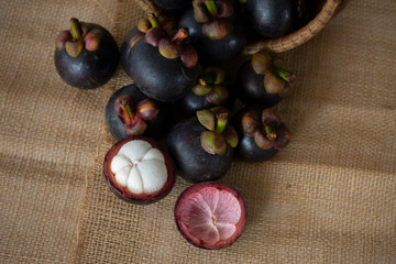 A heap of Mangosteen with and wooden basket placed on Sackcloth