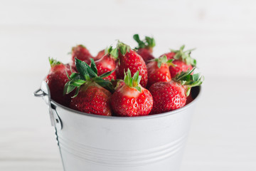 Juicy fresh strawberries in a metal bucket on a white background