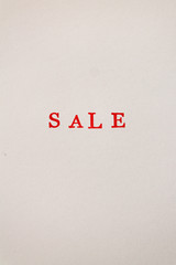 The red word sale stamped on a white paper. Price reduction and promotion in trade and services concept photo. Vertical view