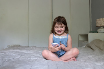 Caucasian child girl preschooler plays with phone, child and gadgets