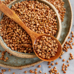 Raw dry buckwheat grain  in a bowl with a spoon