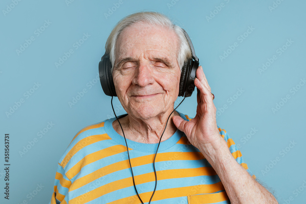Wall mural Happy senior man listening to music with headphones - Wall murals