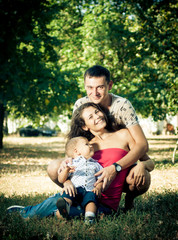 cheerful and beautiful parents with a baby in their arms in the park