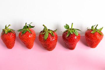 Minimal food concept. Strawberries on a white and pink background. five strawberry isolated. Top view. Free space for text. Tasty berries.