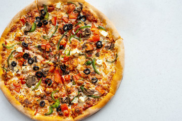Hot delicious pizza with tomatoes, mozzarella, mushrooms, olives, red pepper and Basil on a white background. Copyspace.