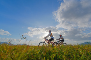 Fototapeta na wymiar family couple lover enjoy the life of riding biking on the fresh field meadow grass, cheerfully life holding hand together on outdoors activity
