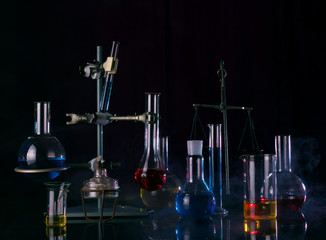 Test tubes, flasks, burner and other laboratory equipment in a smog on a black