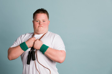 Proud kid with down syndrome holding a skipping rope around his neck