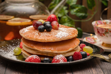 Stack of pancakes with fresh fruit and maple syrup