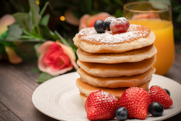Stack of pancakes with fresh fruit and maple syrup