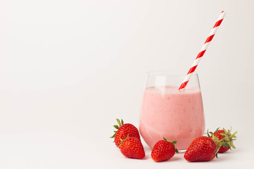 Glass of fresh strawberry milkshake, smoothie and fresh strawberries on pink, white and wooden...