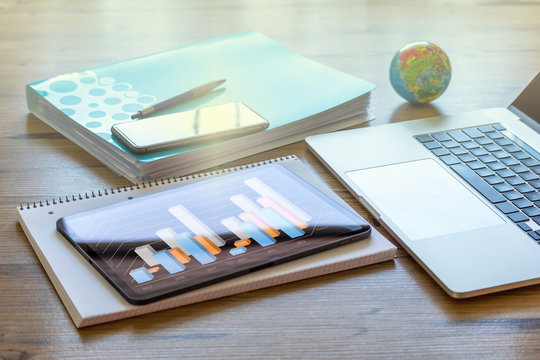 H&ouml;lzerner Schreibtisch Zuhause mit Laptop, Telefon und Tablet mit buntem Balkendiagramm