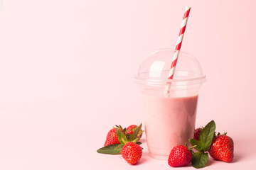 Glass of fresh strawberry milkshake, smoothie and fresh strawberries on pink, white and wooden background. Healthy food and drink concept.