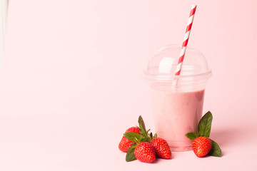 Glass of fresh strawberry milkshake, smoothie and fresh strawberries on pink, white and wooden background. Healthy food and drink concept.