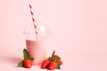 Glass of fresh strawberry milkshake, smoothie and fresh strawberries on pink, white and wooden background. Healthy food and drink concept.