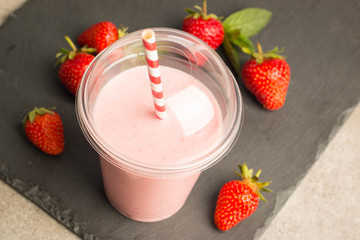 Glass of fresh strawberry milkshake, smoothie and fresh strawberries on pink, white and wooden background. Healthy food and drink concept.