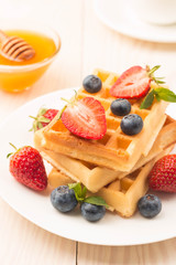 Fresh homemade food of berry Belgian waffles with honey, chocolate, strawberry, blueberry, maple syrup and cream. Healthy dessert breakfast concept with juice
