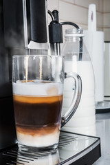glass cup with hot cappuccino prepared in the coffee machine