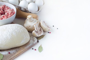 on a white background lies dough, minced meat, mushrooms and spices. sculpt dumplings, place for text on the right