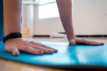 Close up of a woman doing a plank on a blue yoga mat on the living room of her apartment