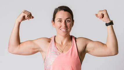 Female athlete flexing her arms - obrazy, fototapety, plakaty