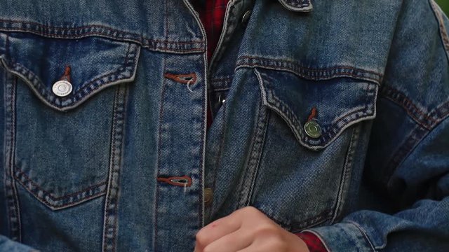 a girl buttons up a denim jacket.