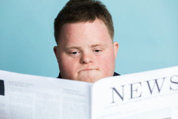 Boy with down syndrome reading a newspaper during the coronavirus pandemic